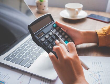 Contractor reviewing government certified payroll documents and wage reports on a construction site office desk.
