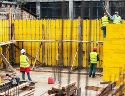 Construction contractor reviewing Davis-Bacon compliance documents and certified payroll forms on a job site.